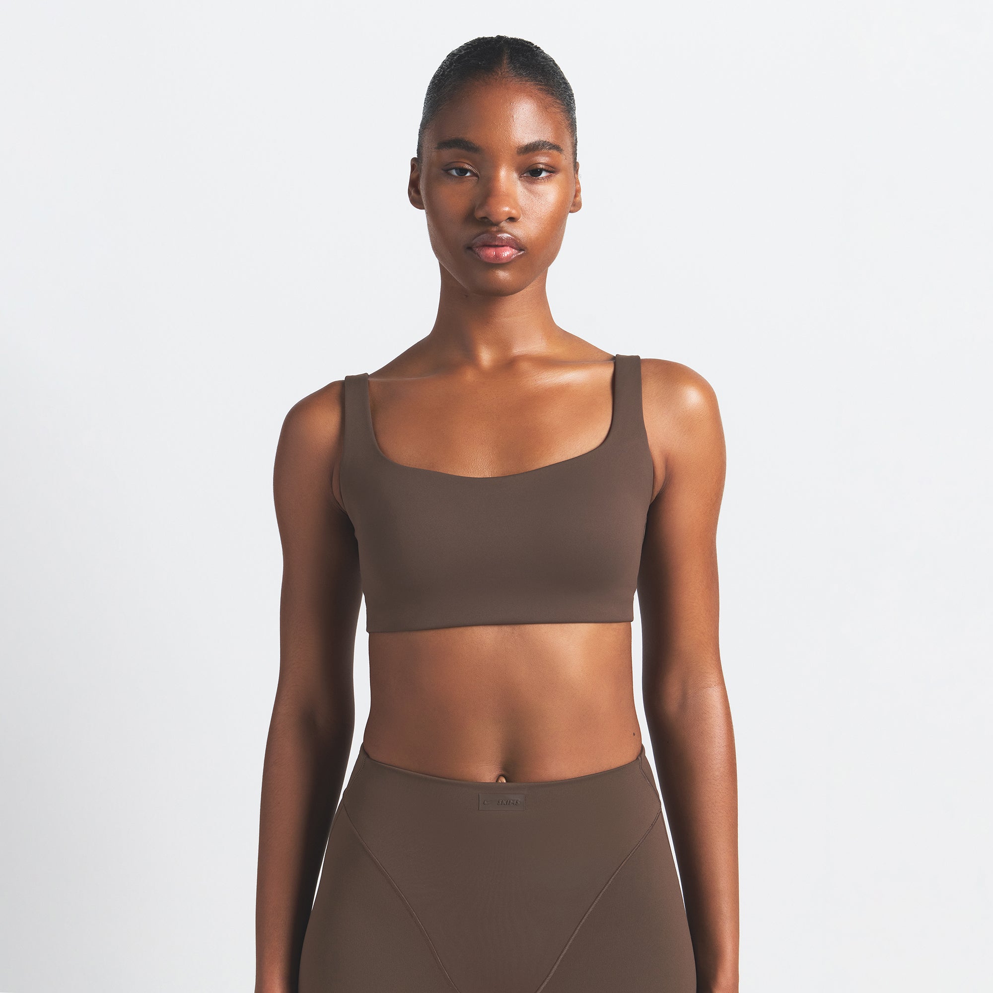 NikeSKIMS MATTE SCOOP NECK BRA | DARK SEPIA ON A MODEL FRONT VIEW