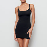 A MODEL STANDS FACING FORWARD WEARING THE FITS EVERYBODY SLIP DRESS | ONYX