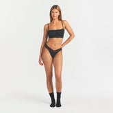LIGHTWEIGHT COTTON WIDE LACE THONG | SOOT TONAL ON A MODEL FRONT VIEW