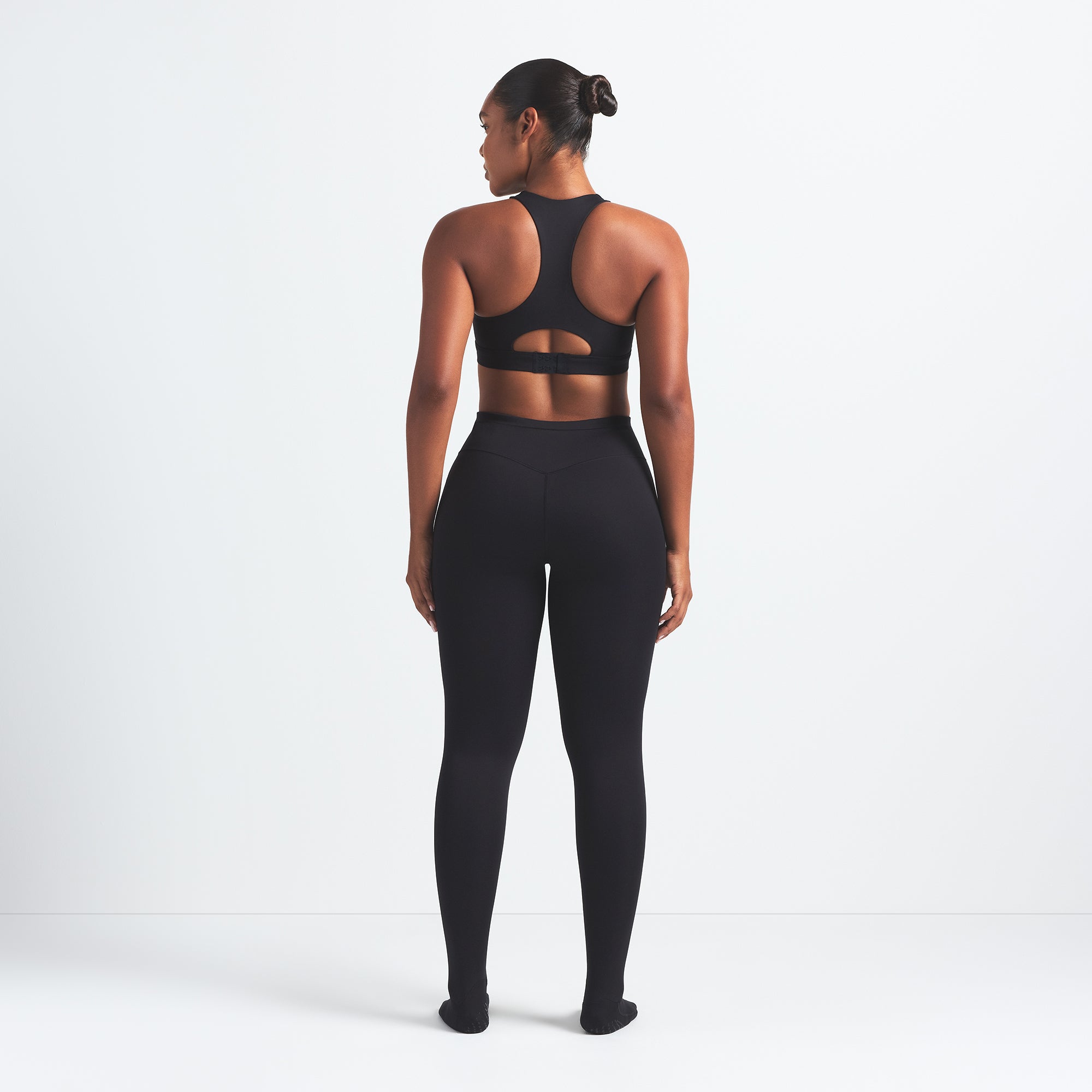 NikeSKIMS MATTE FOOTSIE GRIP LEGGING | OBSIDIAN ON A MODEL BACK VIEW