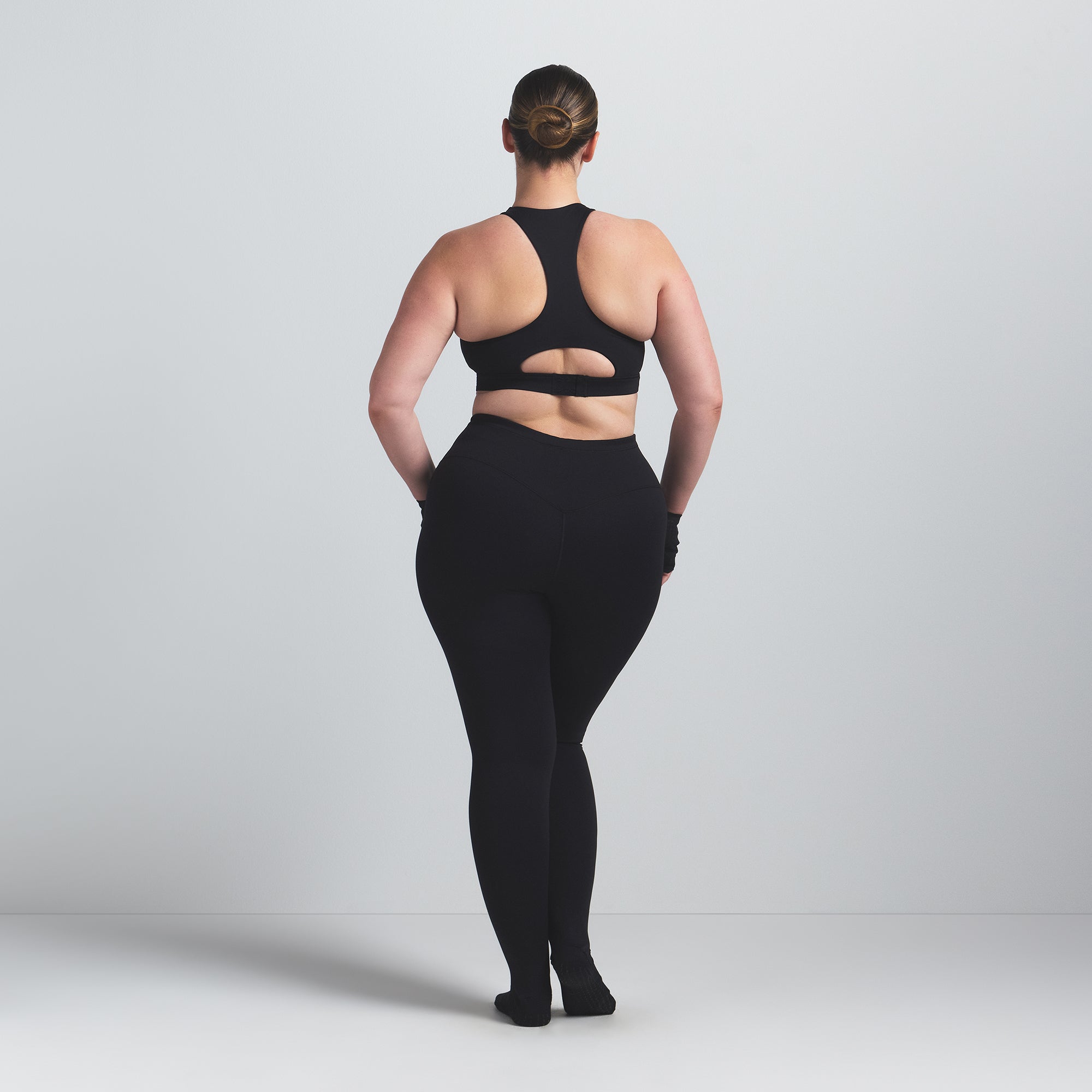 NikeSKIMS MATTE FOOTSIE GRIP LEGGING | OBSIDIAN ON A MODEL BACK VIEW