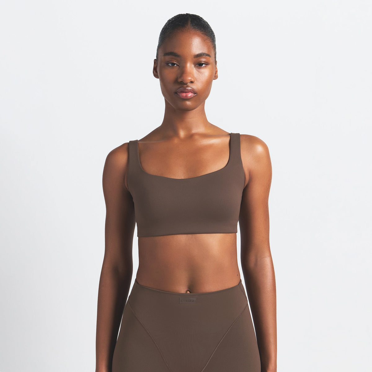 NikeSKIMS MATTE SCOOP NECK BRA | DARK SEPIA ON A MODEL FRONT VIEW