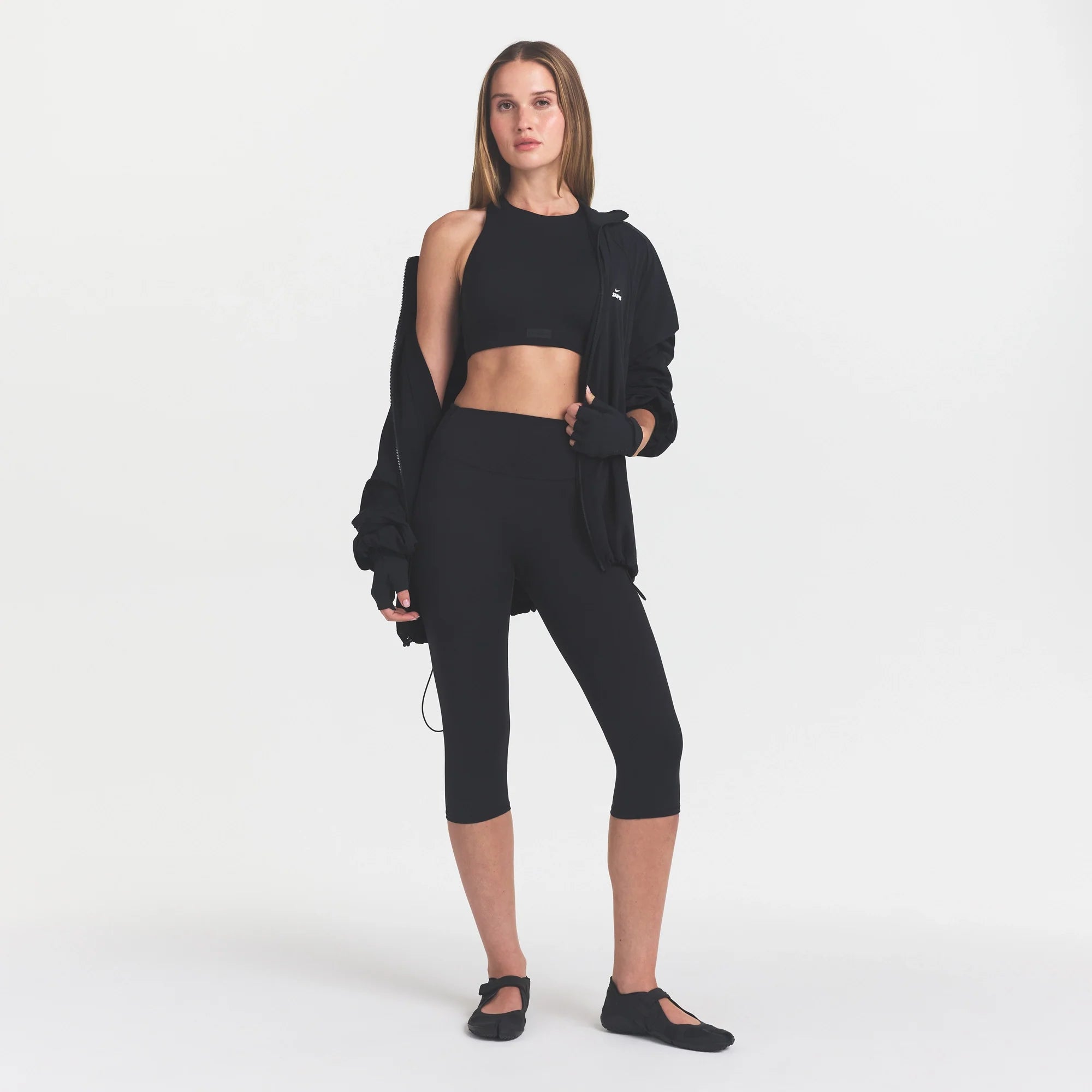 NikeSKIMS MATTE CROP 17" LEGGING | OBSIDIAN ON A MODEL BACK VIEW @ | FOCUS: 0.0, 1.0, 0.9