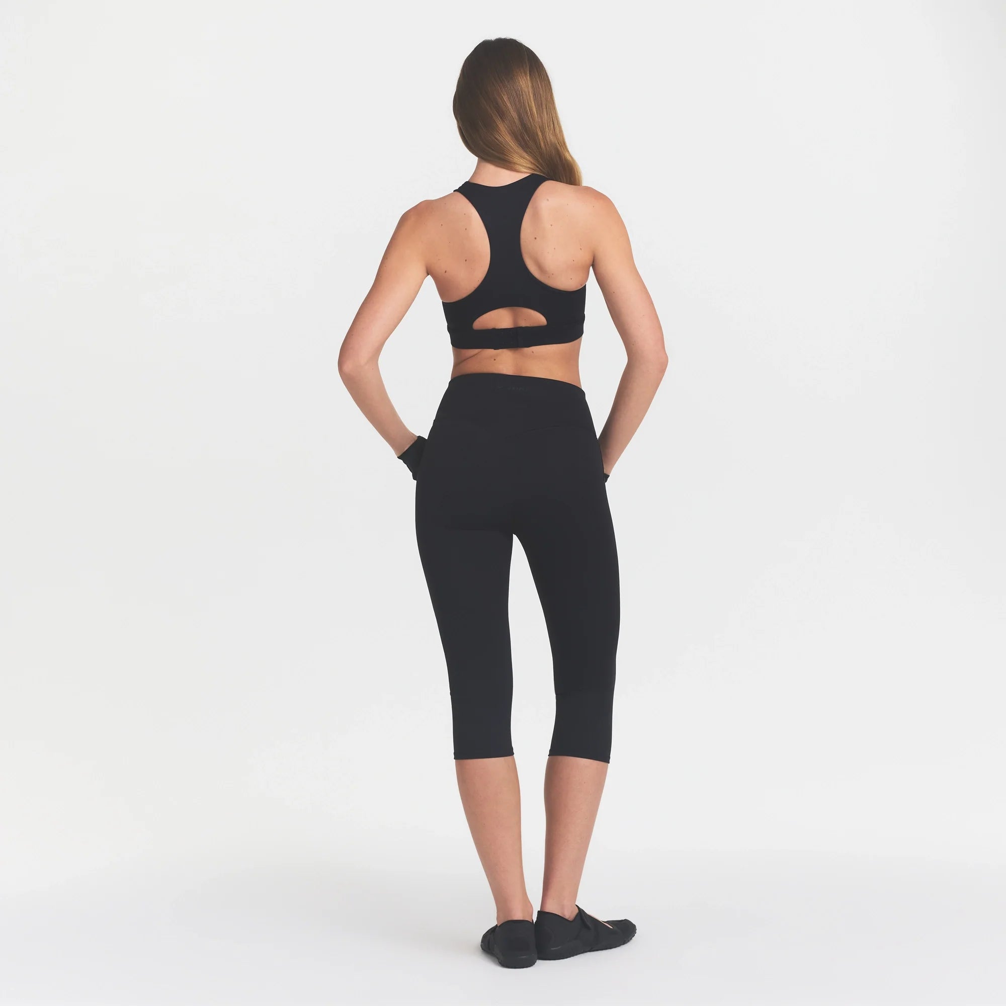 NikeSKIMS MATTE CROP 17" LEGGING | OBSIDIAN ON A MODEL BACK VIEW @ | FOCUS: 0.0, 1.0, 0.9